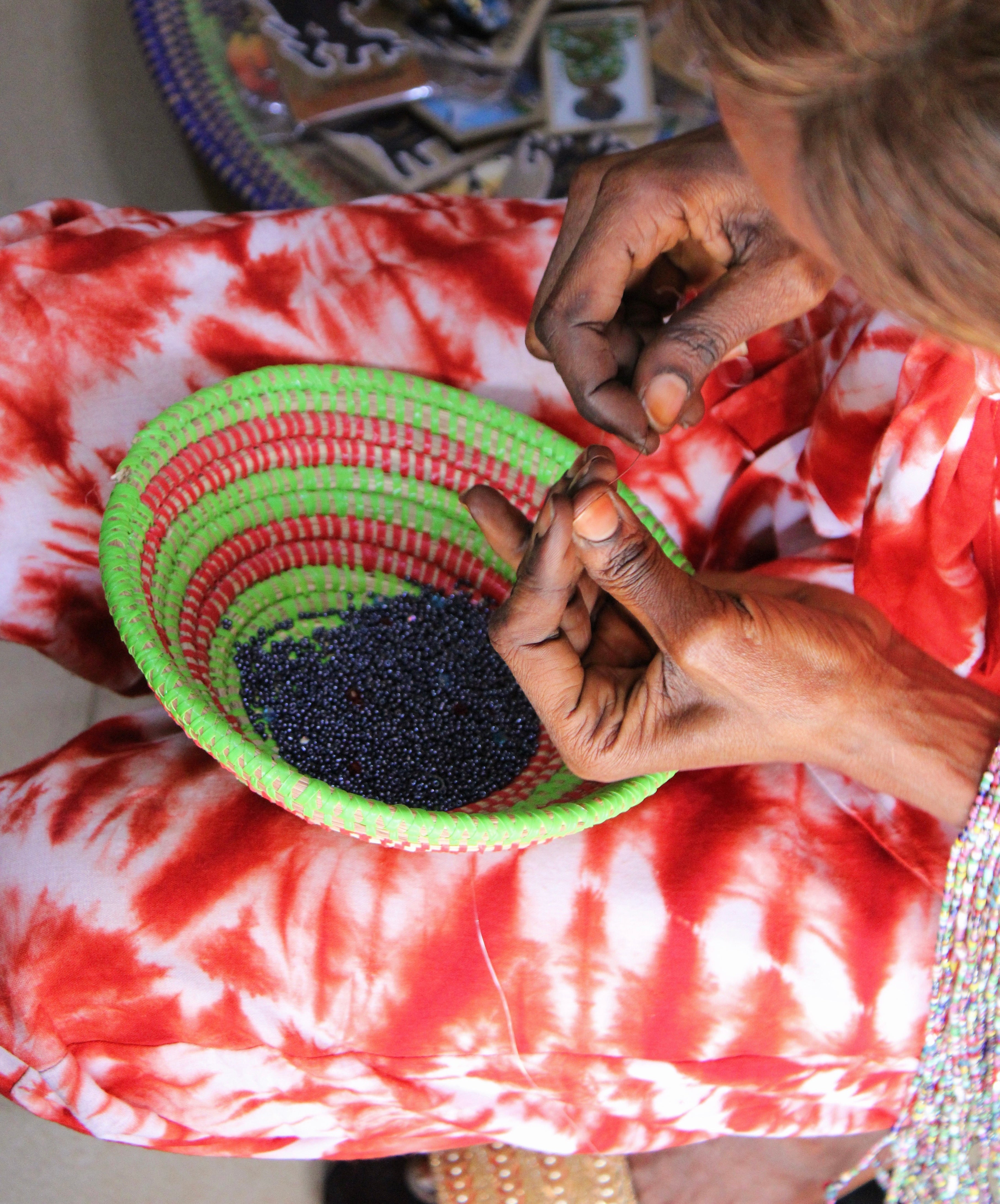 Artisane sénégalaise confectionnant des colliers de ventre en perles noires